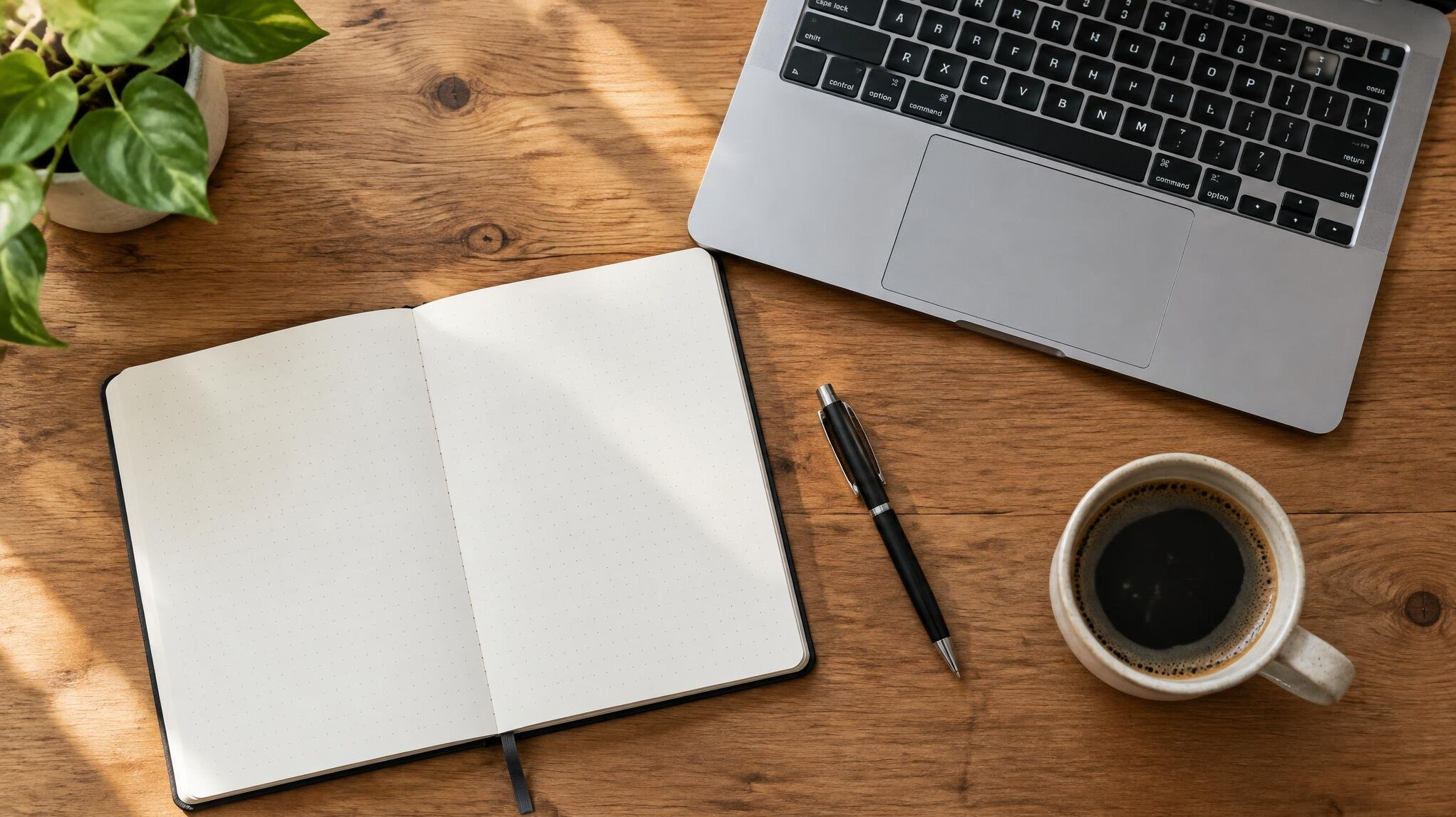 Notebook and laptop on a wooden desk with coffee